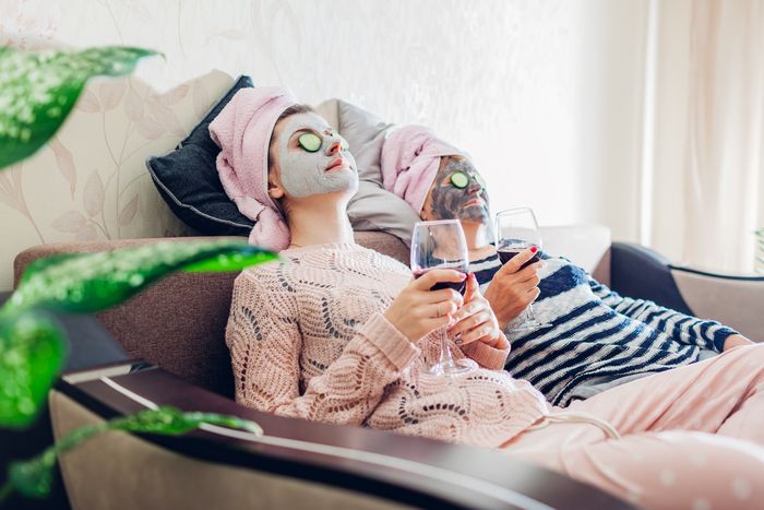 mother and daughter wearing face masks lean back comfortably while sipping wine